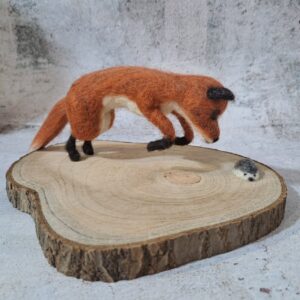 Escultura zorro cazando erizo sobre base de madera